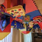 A colourful playroom filled with a variety of toys, including a red slide, plush Minnie Mouse dolls, an activity cube, a play tent with a tunnel, and other interactive toys, all set on interlocking foam mats.