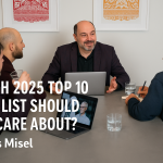 Morris Misel leading a strategic discussion on emerging technologies at a boardroom table, with three colleagues and a laptop displaying a humanoid robot.