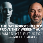 Morris Misel, global futurist and strategist, stands beside a lifelike humanoid robot on a softly lit stage with the Immediate Futures™ logo in the background, symbolising the Imagination Gap and the future of human–AI collaboration.