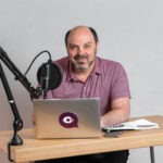 Morris Misel, business futurist and keynote speaker, speaking into a microphone while working at a desk during a radio interview
